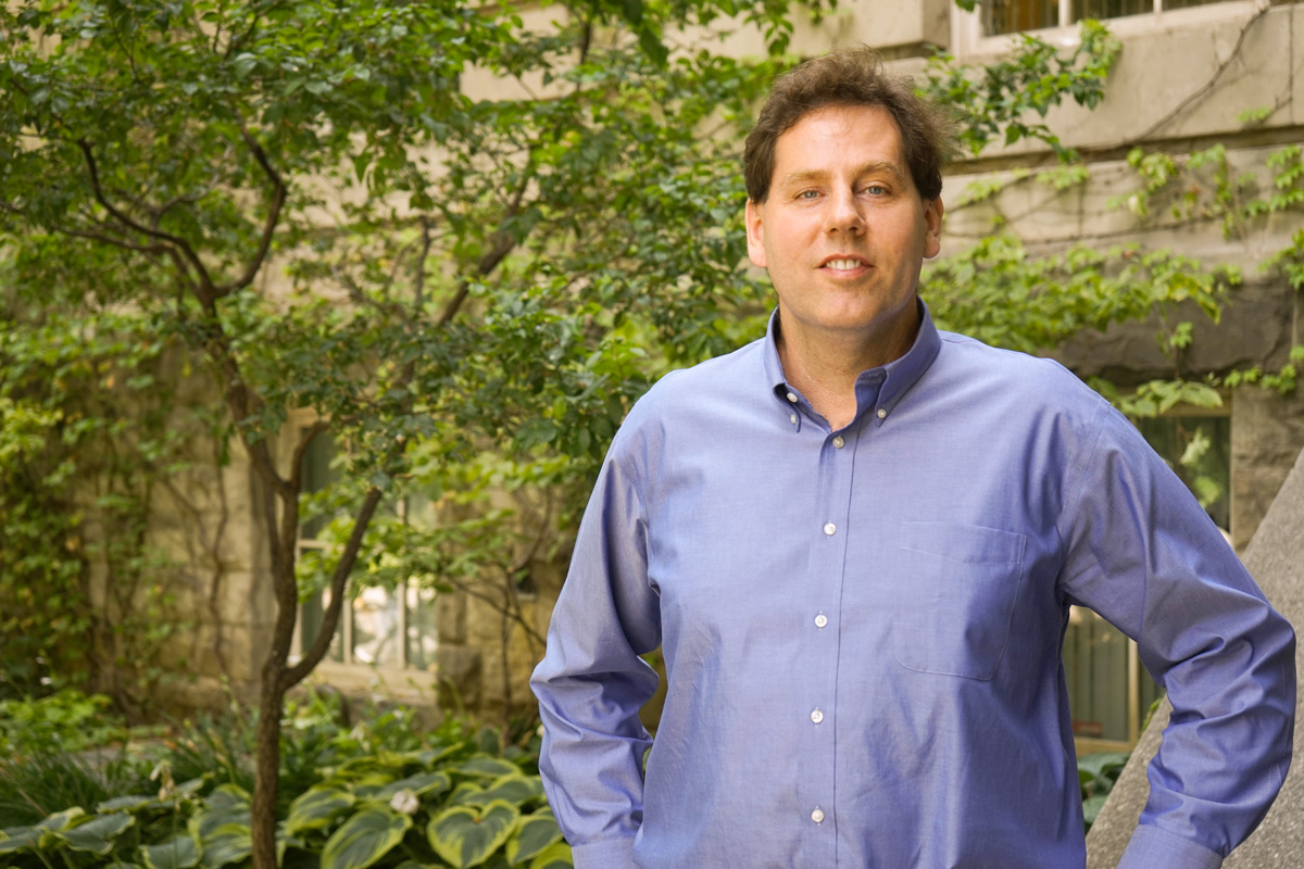 Professor standing outside with trees in background