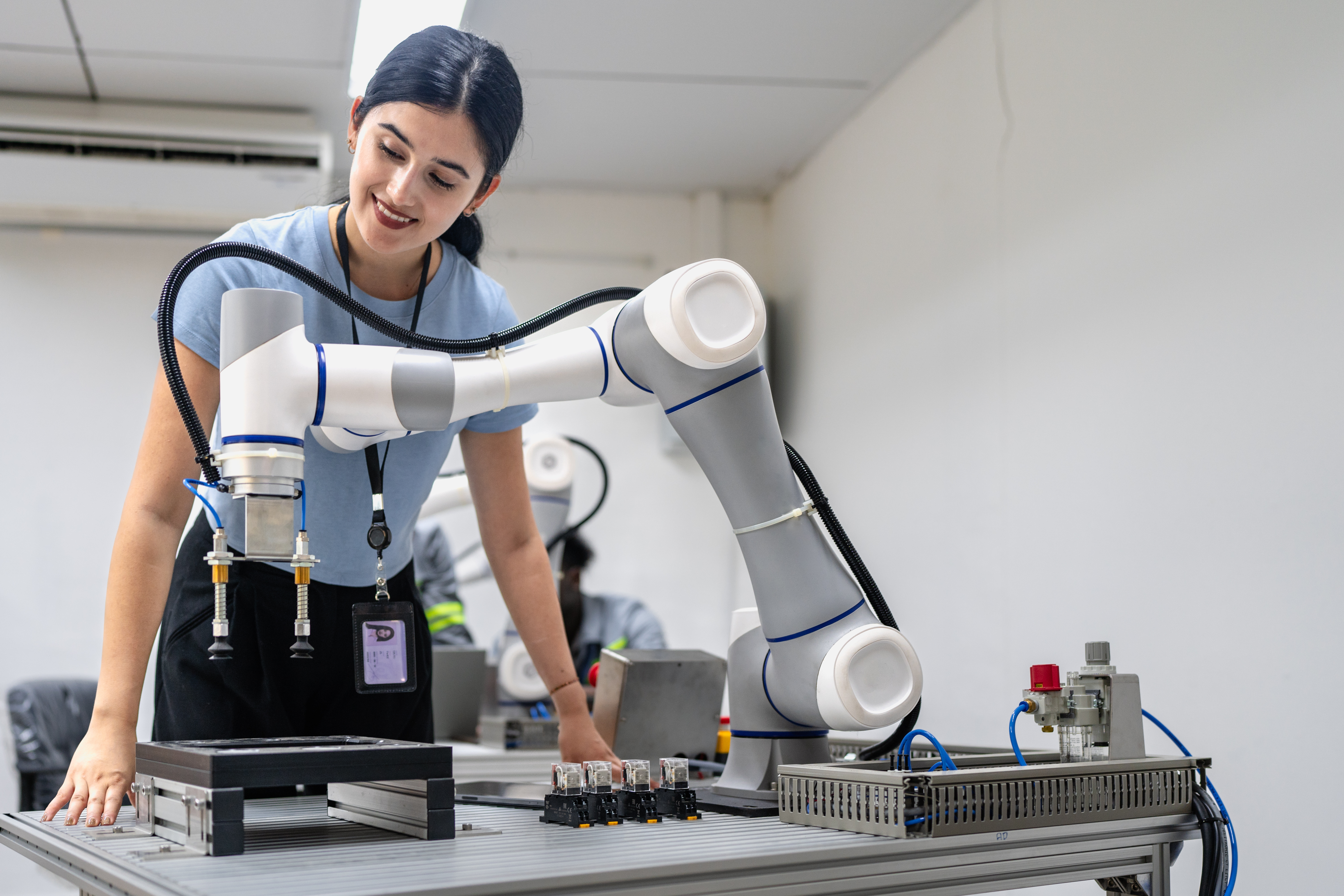 Hispanic engineer woman working on AI technology in robotics electronics engineering laboratory. University students' research project is programming robot machine with intelligent mechanical control